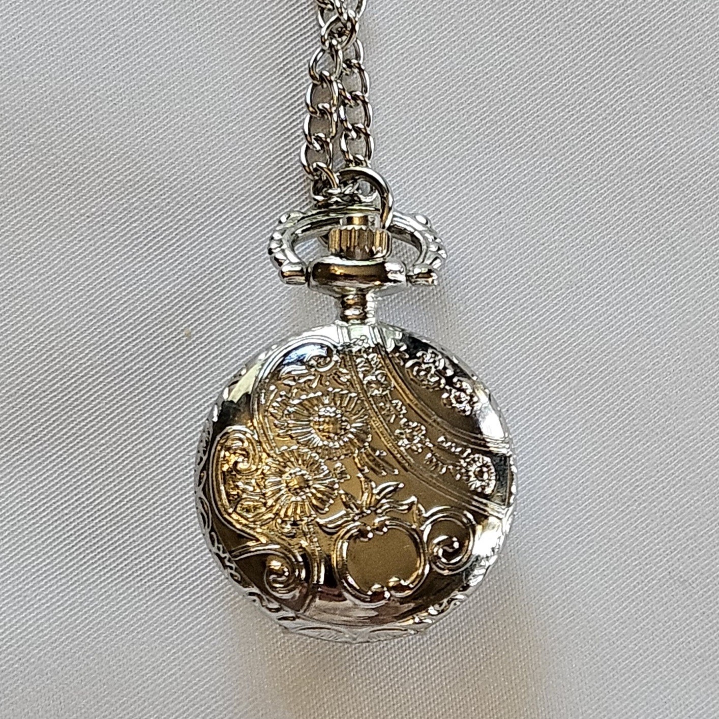 Silver-toned quartz pocket watch necklace with a filigree design.