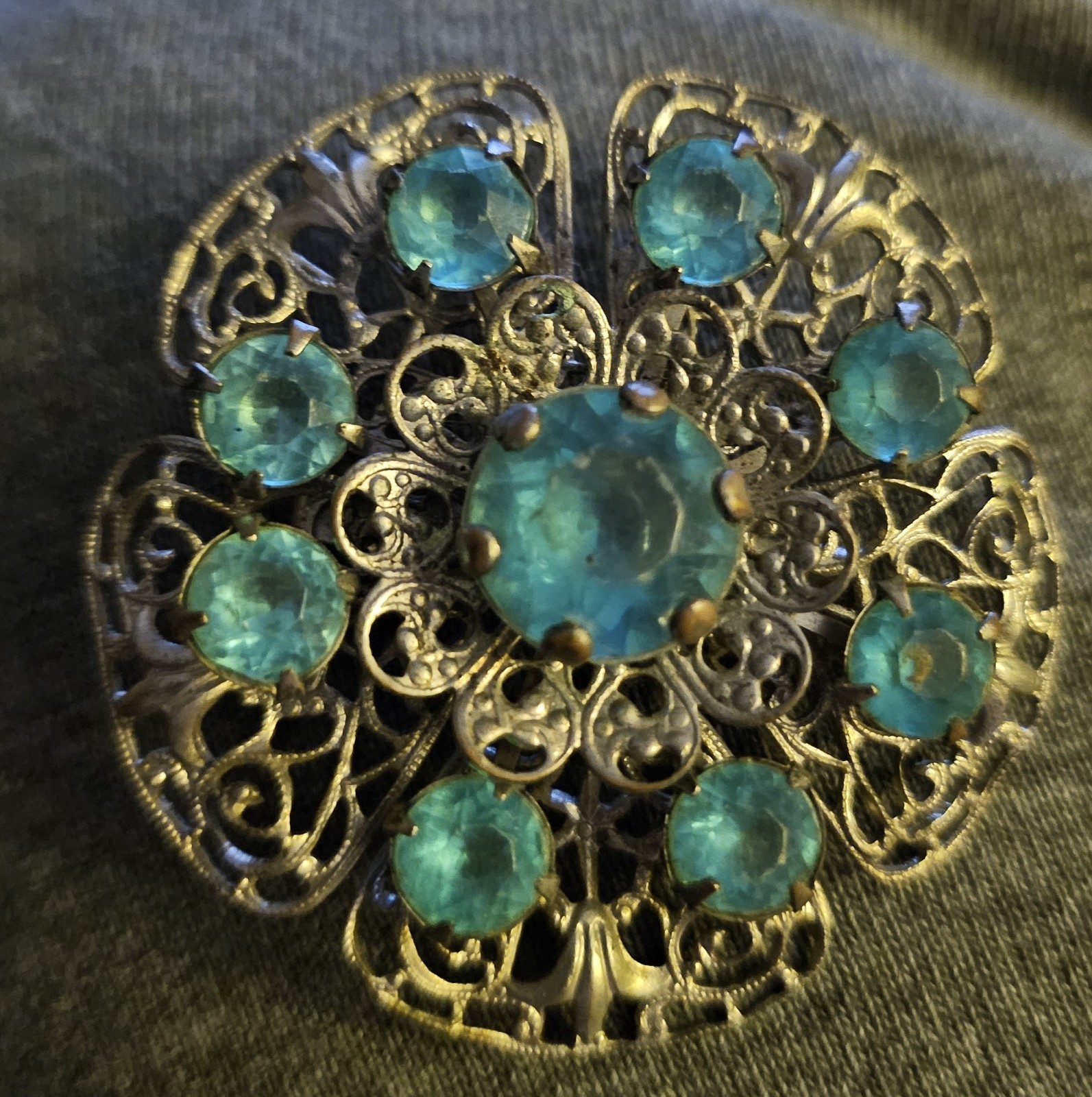 VTG Brooch featuring blue rhinestones set in a silver-tone filigree metal.