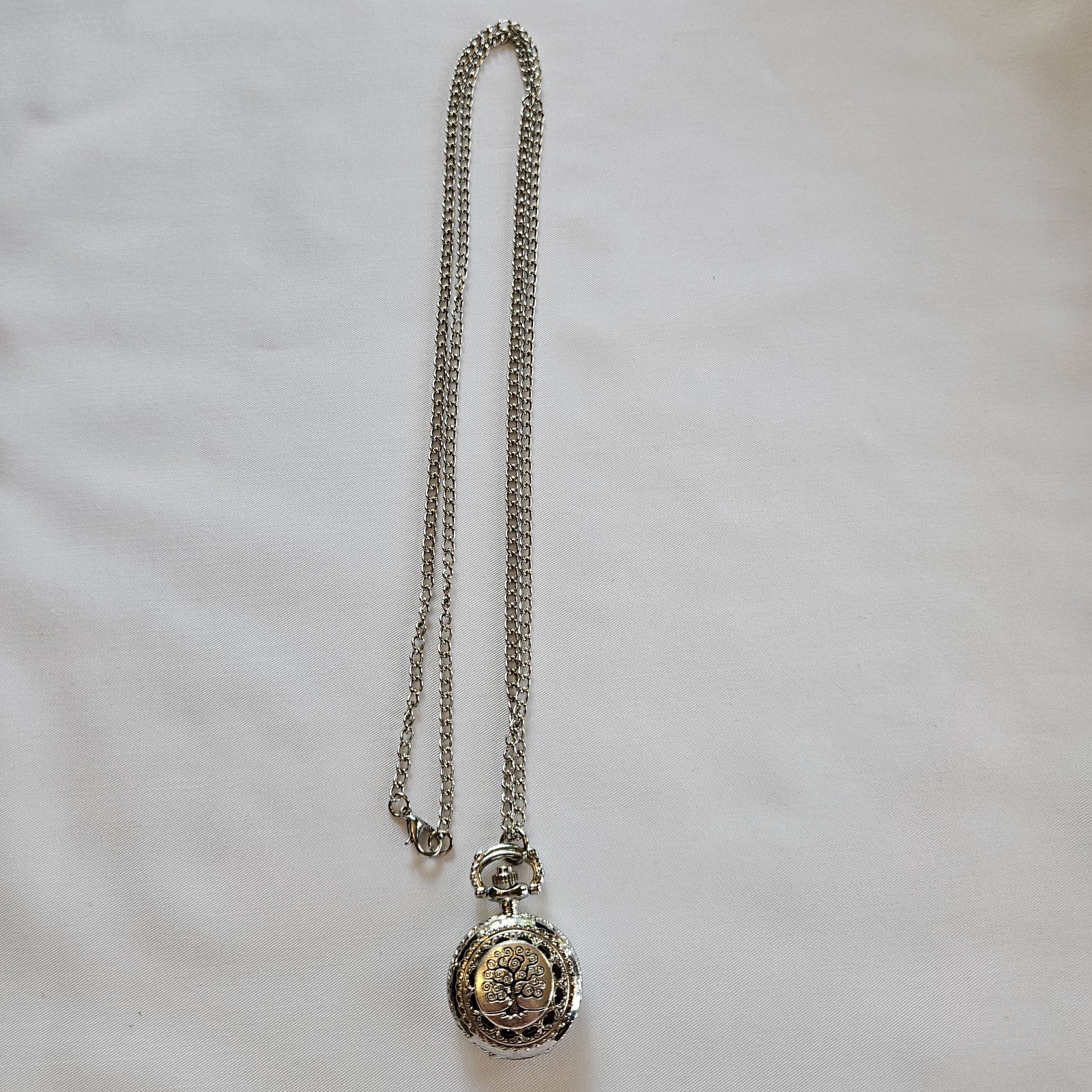 Silver-toned quartz pocket watch necklace with a filigree design.