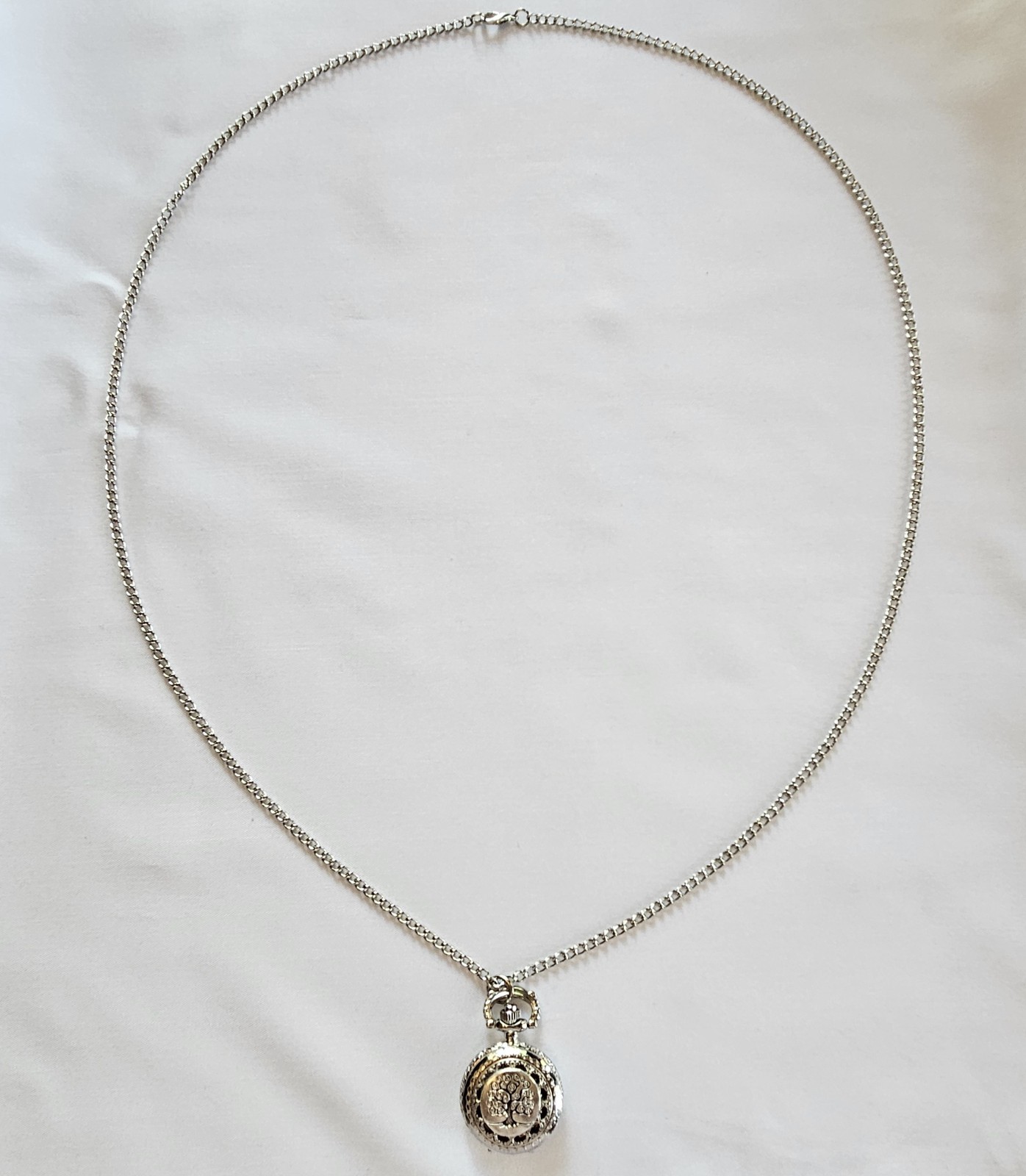 Silver-toned quartz pocket watch necklace with a filigree design.