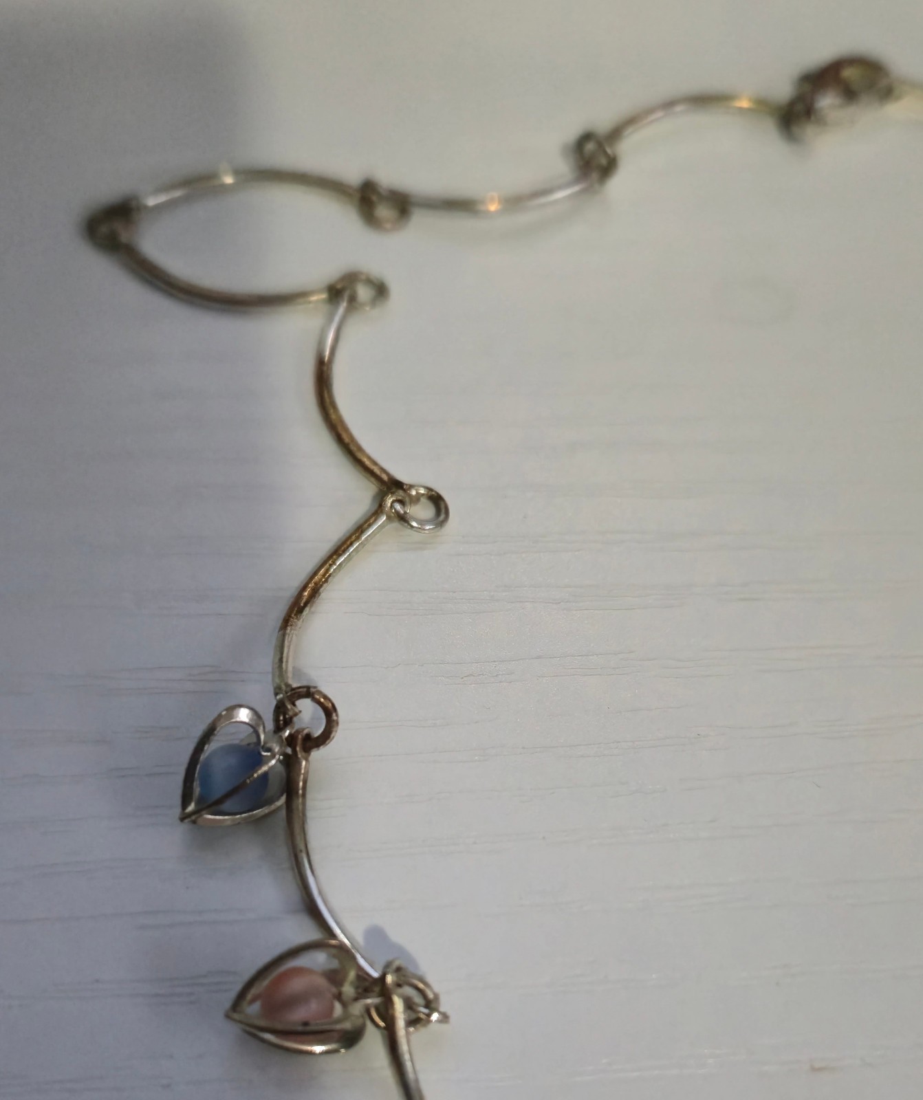 9 multicolor heart caged bead charms on a silvertone necklace