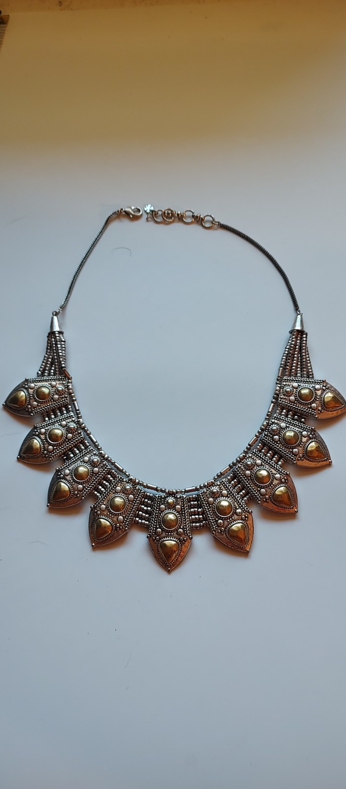 Bohemian design necklace with curved row of repeating leaf-or shield- shape pane