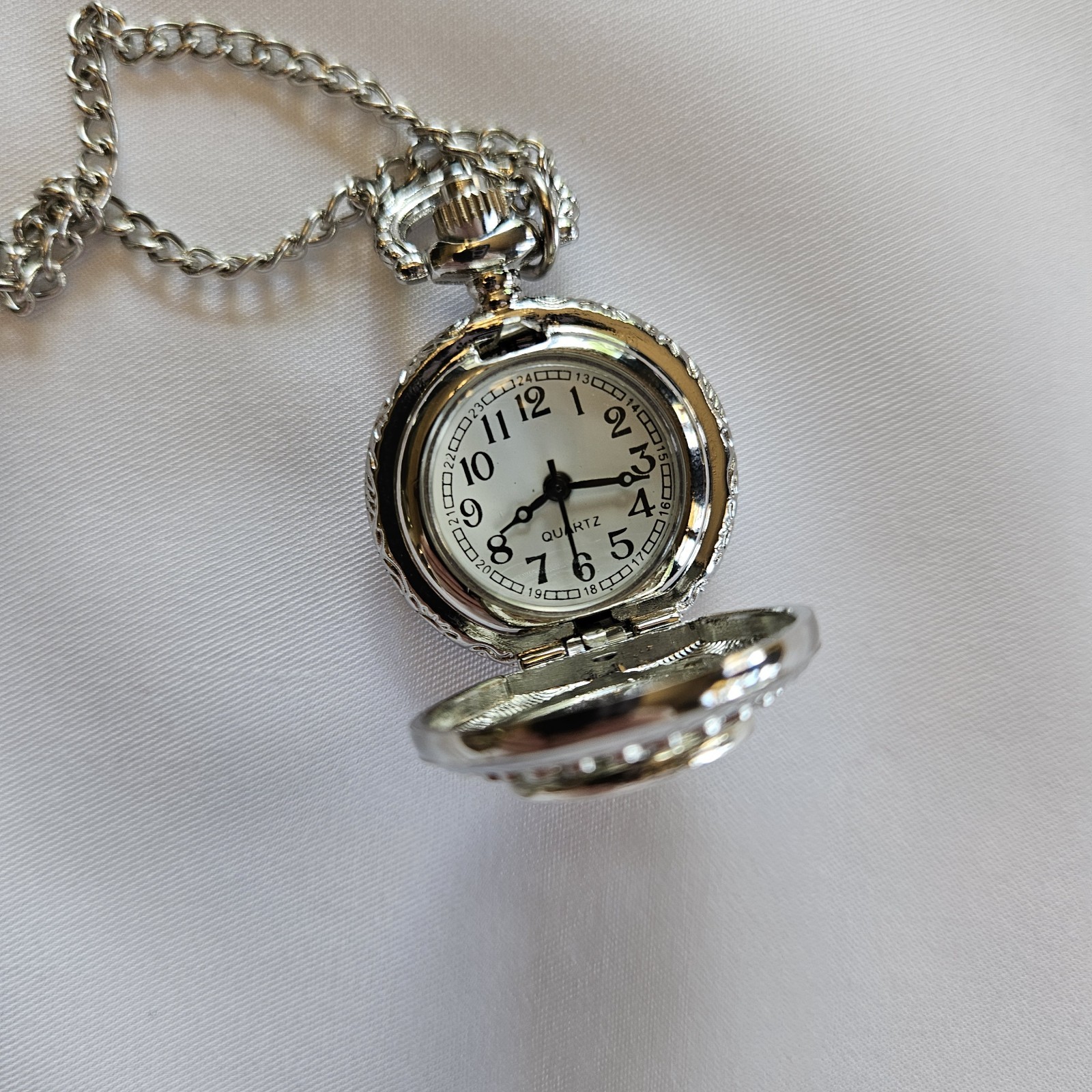 Silver-toned quartz pocket watch necklace with a filigree design.