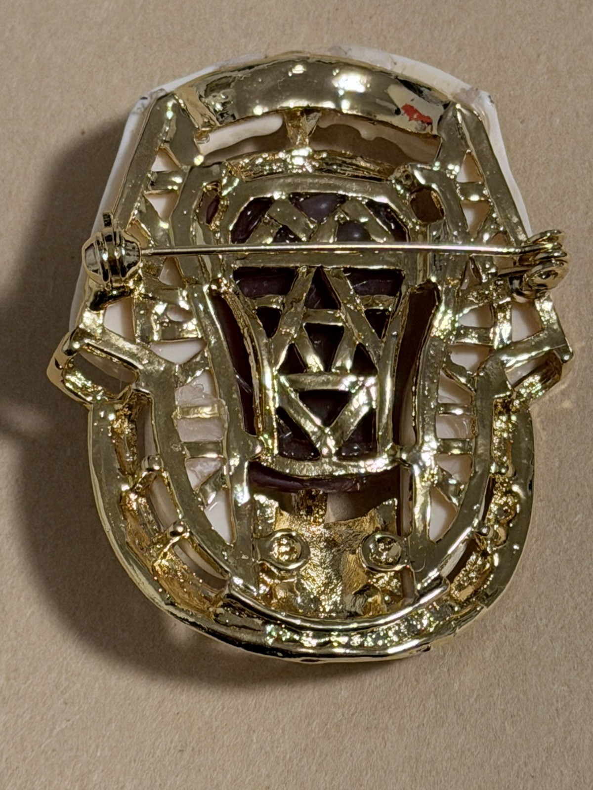 Egyptian Revival King Tut brooch featuring gold metal, white lucite, red resin