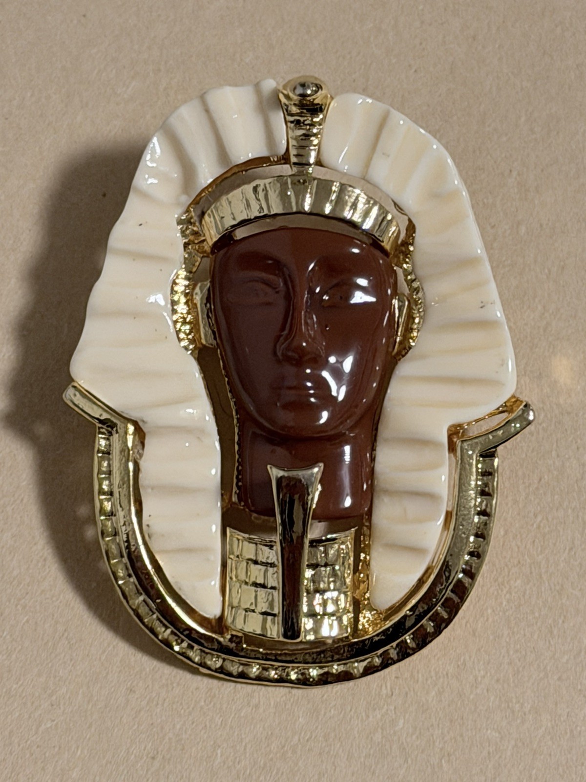 Egyptian Revival King Tut brooch featuring gold metal, white lucite, red resin
