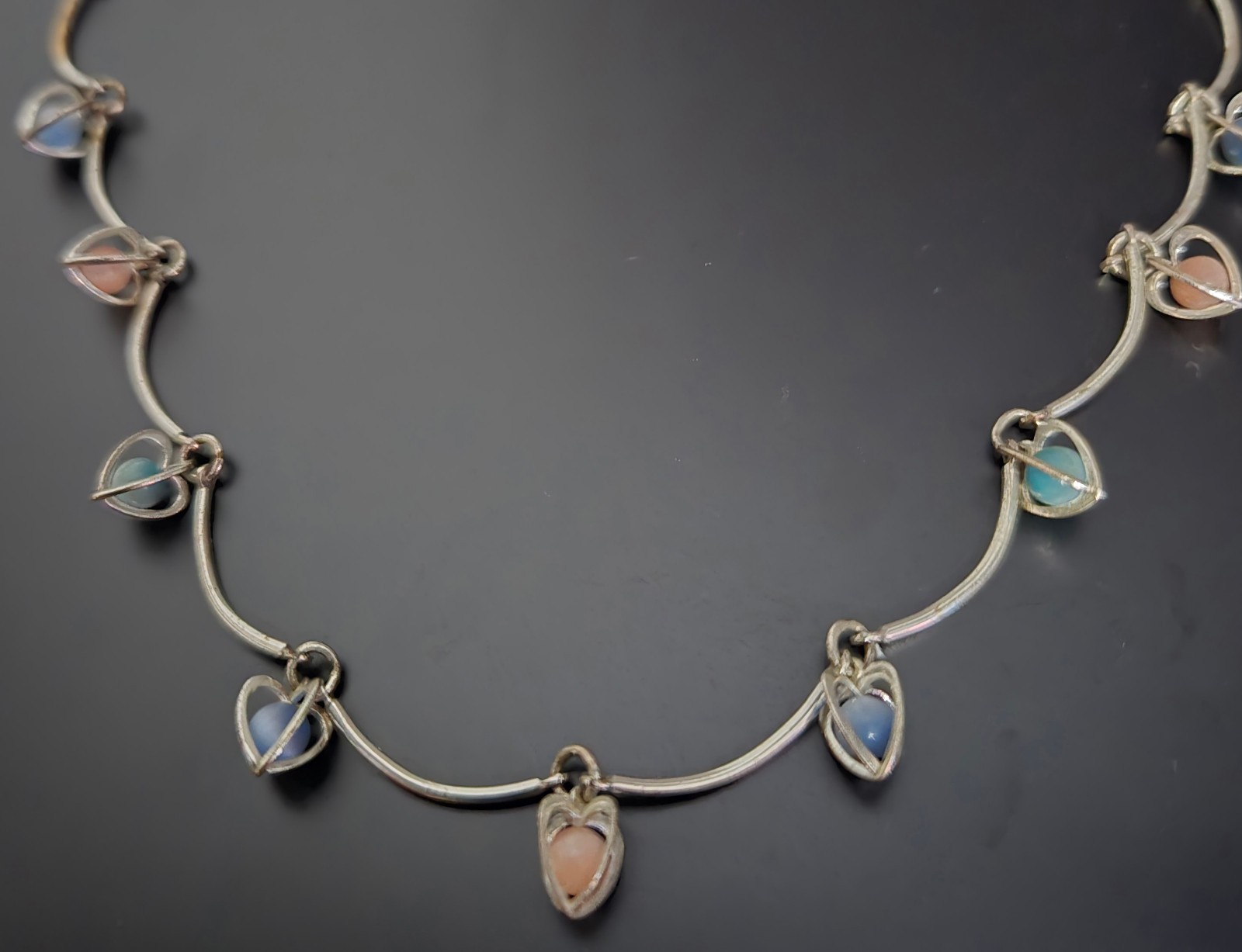 9 multicolor heart caged bead charms on a silvertone necklace