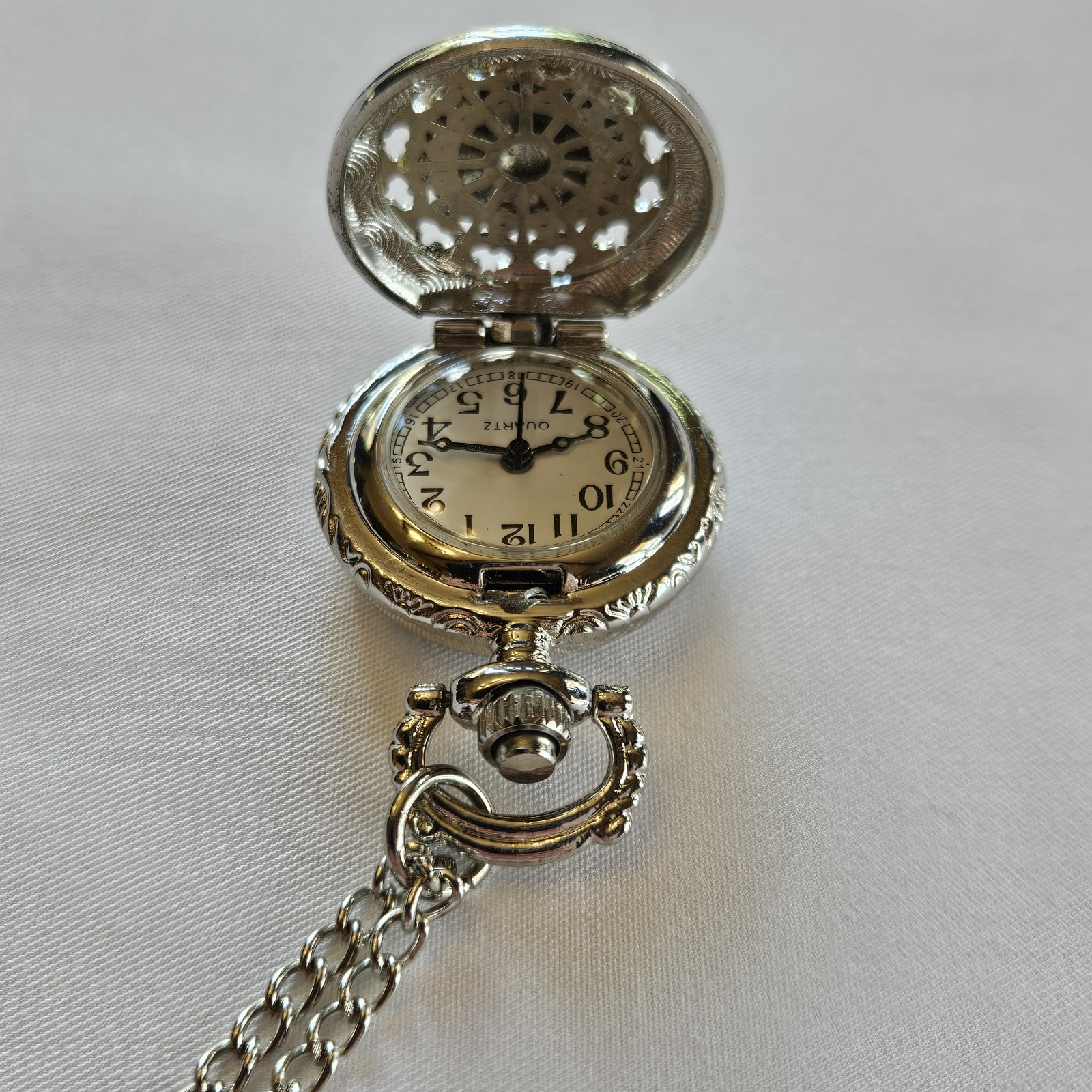 Silver-toned quartz pocket watch necklace with a filigree design.