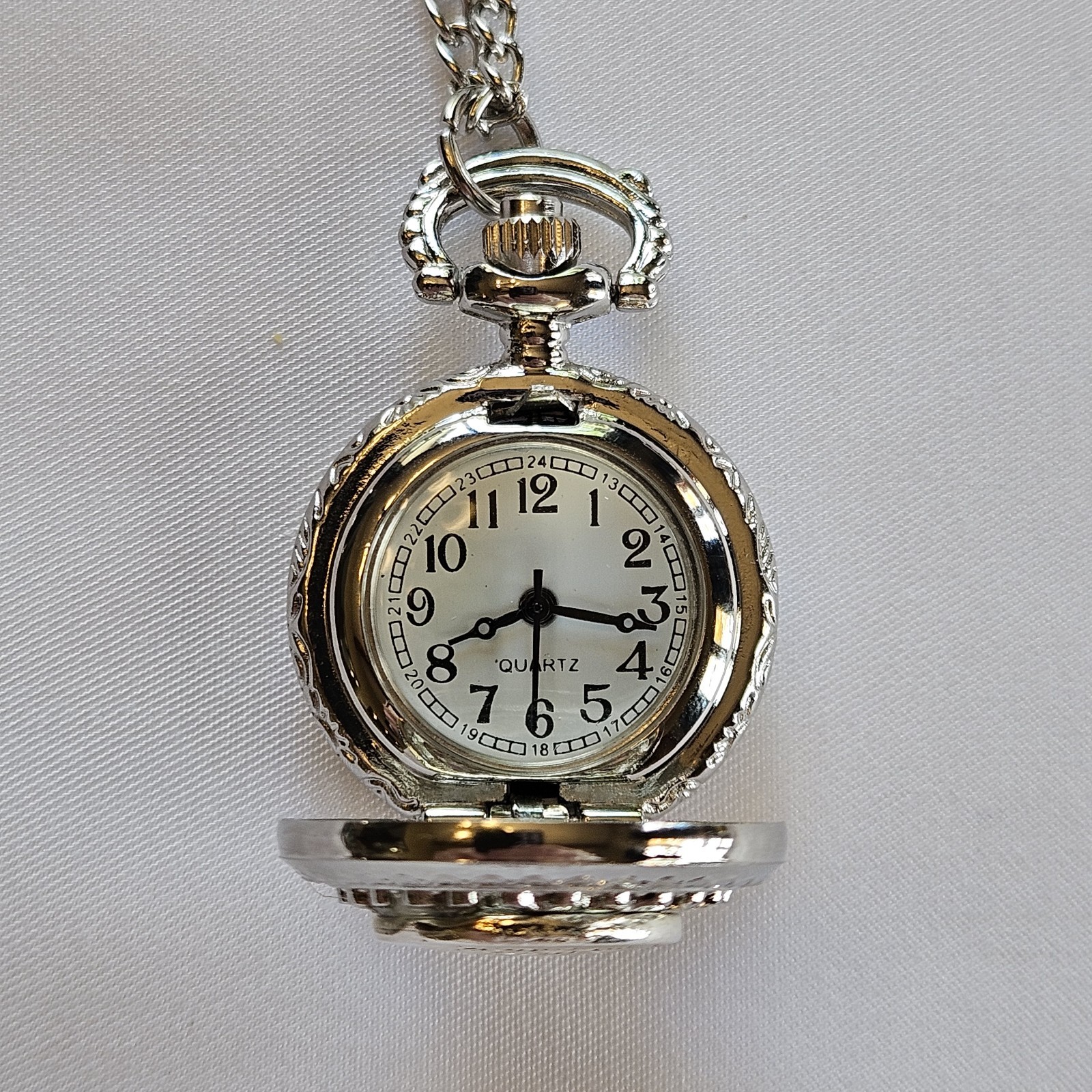 Silver-toned quartz pocket watch necklace with a filigree design.