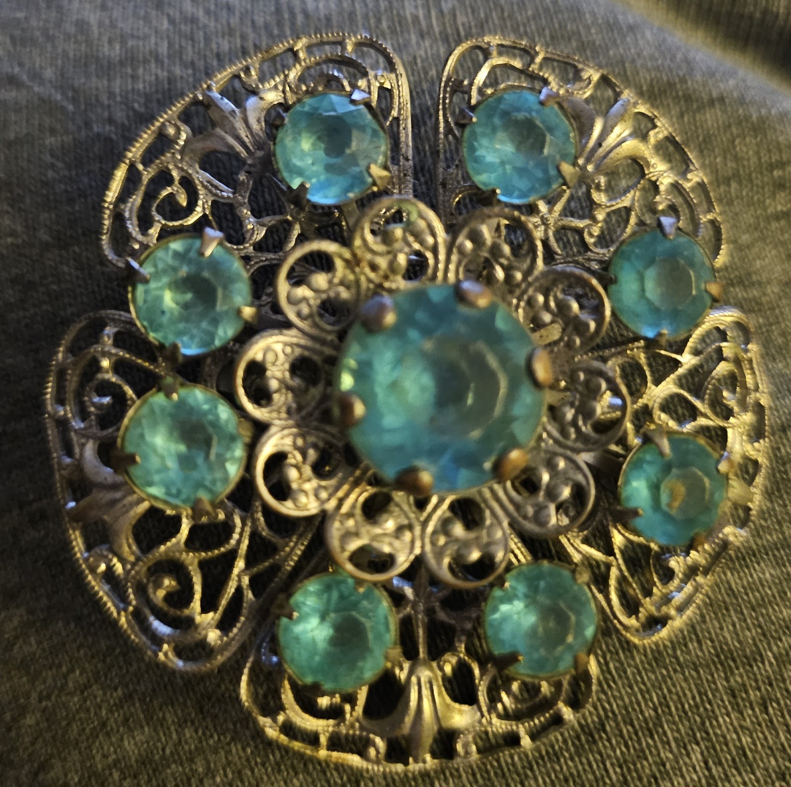 VTG Brooch featuring blue rhinestones set in a silver-tone filigree metal.